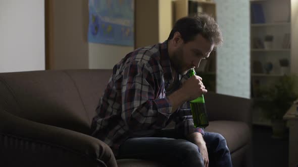 Drunken Man Sitting on Sofa and Looking at Beer Bottle, Having Hiccups, Alcohol