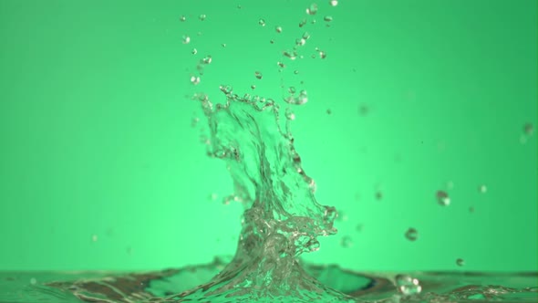 Super Slow Motion Sprays Water on a Green Background