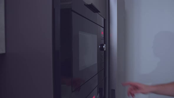 Man Puts Food on a Plate in the Microwave Oven