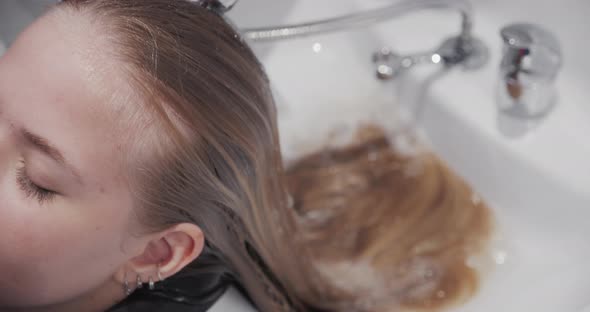 Hairdresser Rinsing Relaxed Woman'S Long Hair
