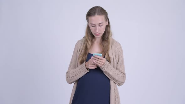 Happy Young Pregnant Woman Thinking While Using Phone