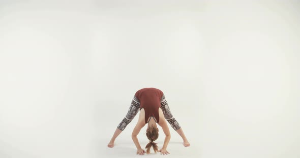 Young attractive woman performing Yoga routine on a white studio background