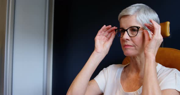 Senior woman adjusting eyeglasses in clinic 4k