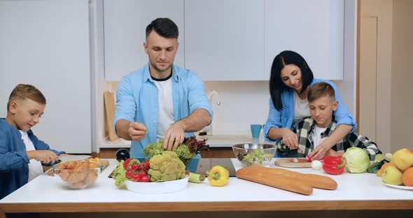 Family Which Together with Children Preparing Fresh Vegetable Salad for Dinner