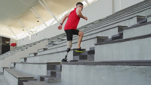 Caucasian disabled male athlete with prosthetic leg training, running up stairs