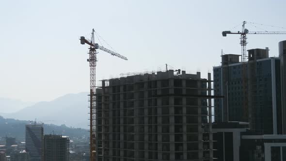 Tower Crane on a Construction Site Lifts a Load at High-rise Building. Timelapse.