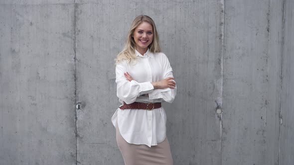 Confident Young Woman Standing Near Shabby Wall and Looking at Camera