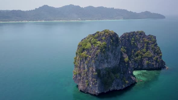 Aerial arch shot of large rock formation in blue ocean in Thailand - camera circling