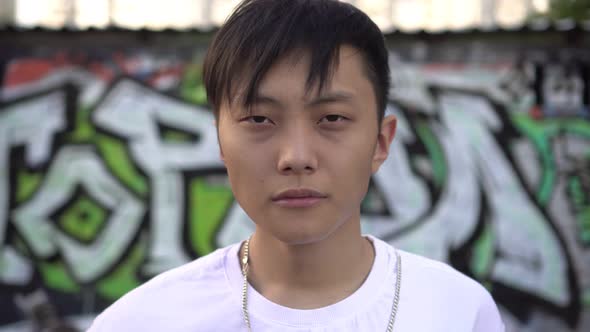Portrait of a Young Asian Man Against a Background of Street Graffiti