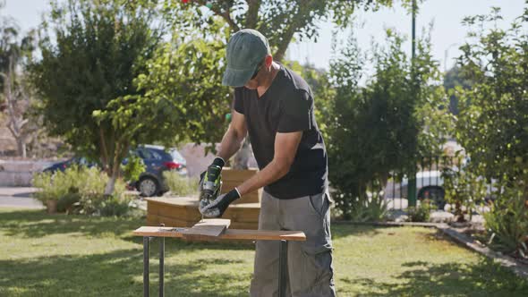 Slow motion of a man using an electric screwdriver to drive a screw into wood