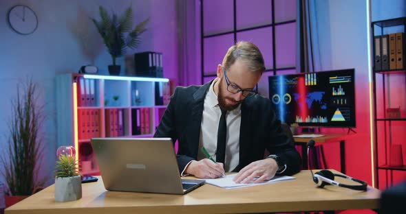 Businessman in Formal Suit Working with Financial Reports and Viewing Information on laptop