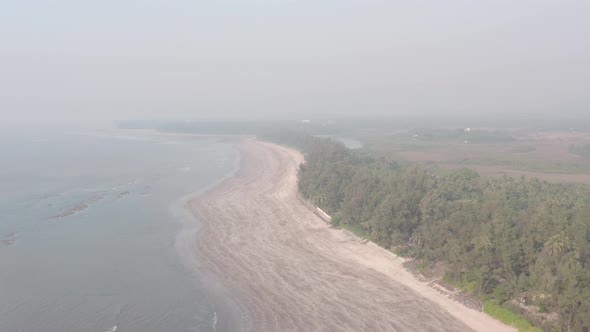 High drone shot over empty sandy beach on a hazy day