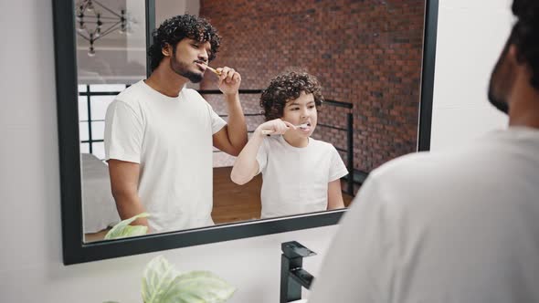 Brothers with Curly Hair Brush Teeth Together in Bathroom