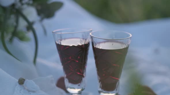 Two Wedding Crystal Glasses with Red Wine on the Background of a Bouquet of White Roses with