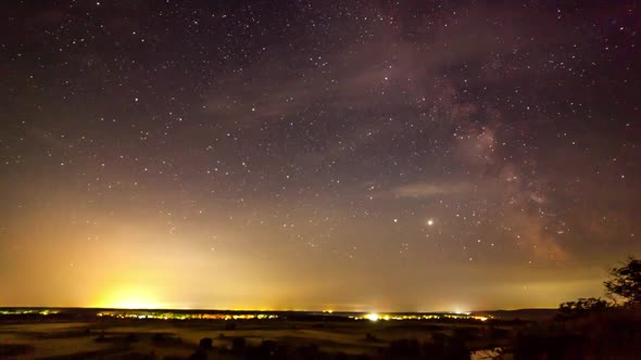 Starry Night in Mountains Time Lapse. Milky Way Galaxy Stars Moving Over Countryside Traffic. Night