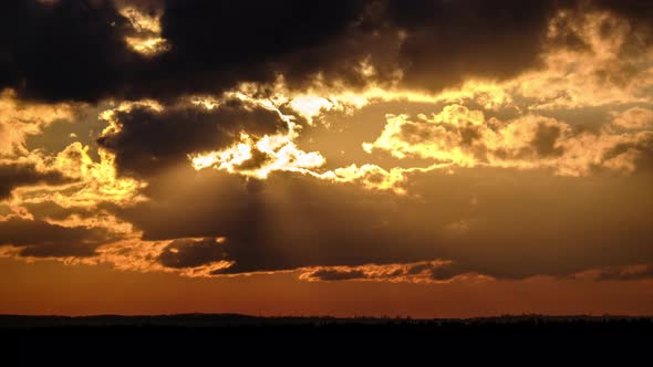Dramatic Sunset with Sun Rays in Sky Through Orange Layered Clouds Timelapse