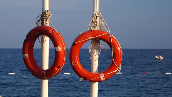 Two Lifebuoys Hang on a Pole in the Sea, People Are Bathing