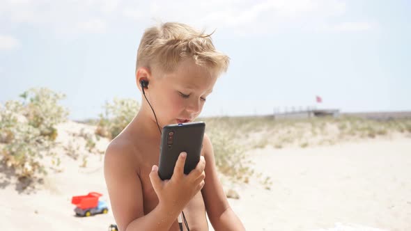 Funny Child Using a Smartphone on the Beach.