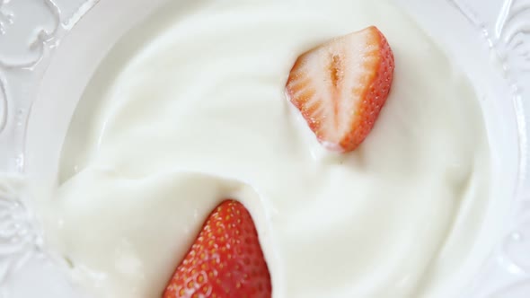 Strawberries being falling in whipped cream