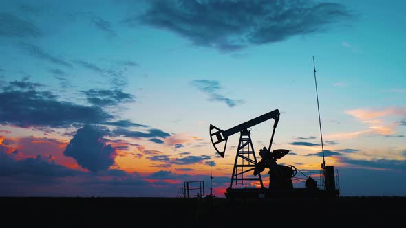 Silhouette Working Oil Pump in Deserted District at Sunset