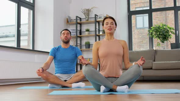 Couple Meditating in Yoga Lotus Pose at Home