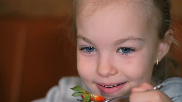 Little Girl Eats Dessert with Fresh Strawberries and Drinks Tea