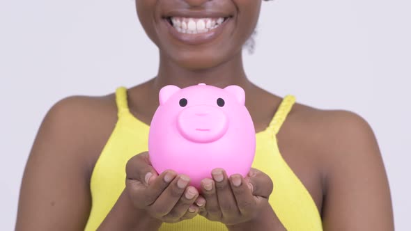 Happy Young African Woman Smiling While Holding Piggy Bank