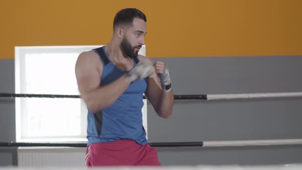 Middle Shot of Muscular Boxer Punching Air in Boxing Ring