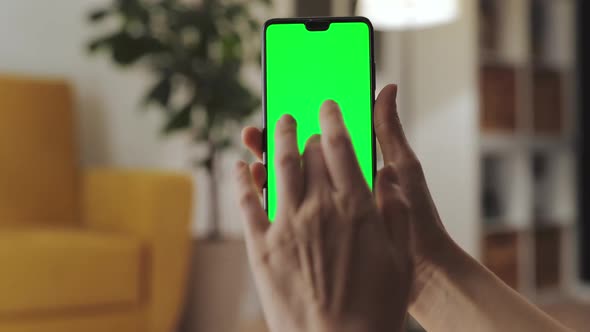 Handheld Camera Point of View of Woman at Modern Room Using Phone With Green Mockup Screen