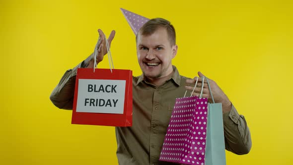 Smiling Man Showing Black Friday Inscription on Shopping Bags, Celebrating, Rejoicing Good Discounts
