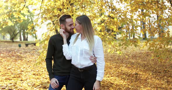 Admiring Couple in Love Stands in Autumn Park Caresses and Kisses Each Other