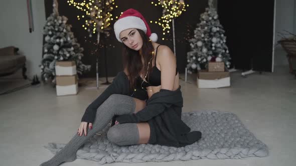 Hot Brunette in New Year's Hat and Lingerie Thoughtfully Poses at Camera