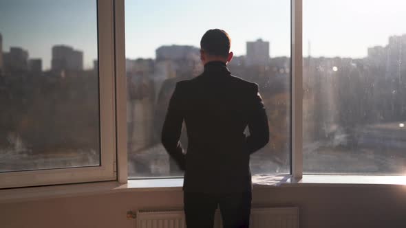 Contemplative Businessman Looking at the City Through a Large Window Thoughtful Entrepreneur