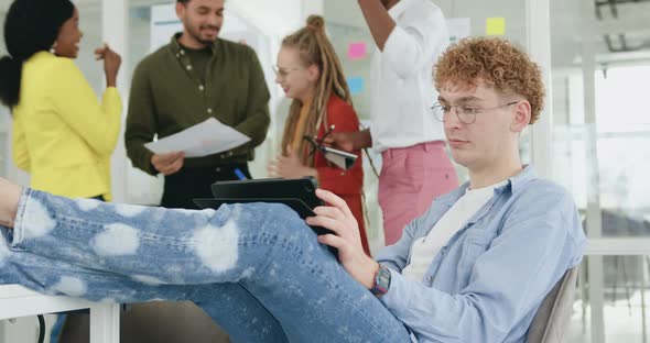 Guy in Glasses Putting His Legs on the Table and Working on Tablet pc 