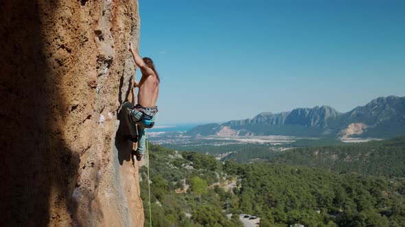 Fit Man Rock Climbing Up Mountain Focusing on His Next Move Reaching Rock Holds