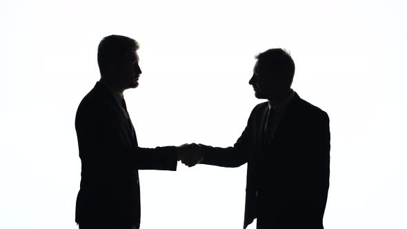 Silhouettes of Men in Business Suits Shake Hands on a White Background in Studio