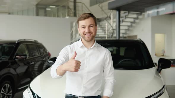 Portrait of a Young Man Near a New Electric Car in a Car Dealership
