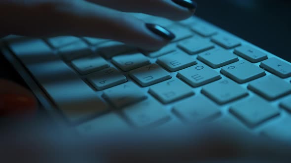Low Angle Shot of Female Hands Typing on a Keyboard in a Backlit Dark Office