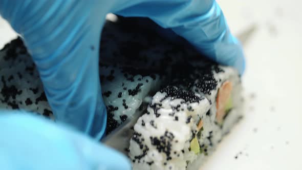 Chef in Restaurant Preparing and Cutting Sushi Rolls