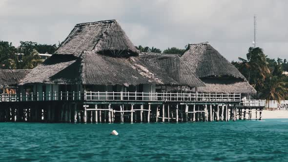 African Restaurant with Thatched Roof on Wooden Poles Above the Ocean