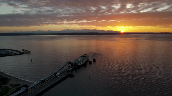 Aerial shot of ferry docking in Washington state with sun setting behind it.