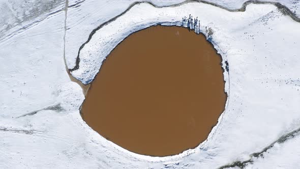 Aerial top down rotation of a crater lake Birkat Ram, in snow on Mount Hermon, Israel, The mountain