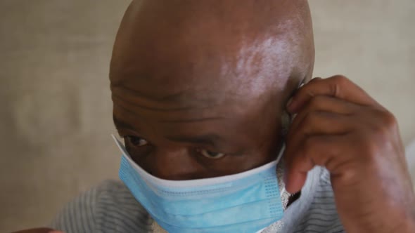 Close-up of portrait of african american senior man wearing face mask at home