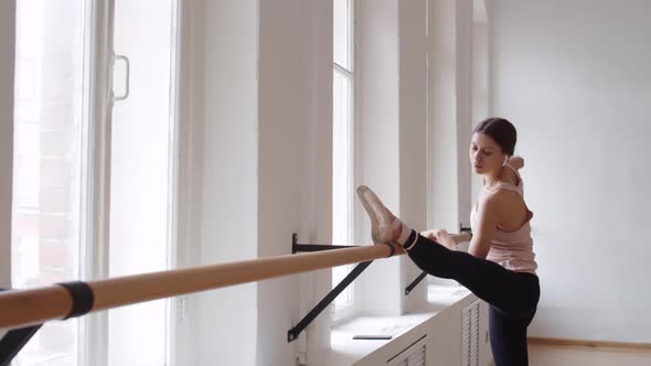 Young Ballerina Stretching Alone in Studio