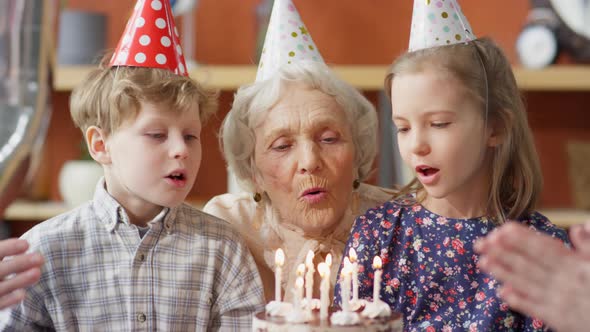 Grandmother and Kids Blowing Candles on Birthday Cake