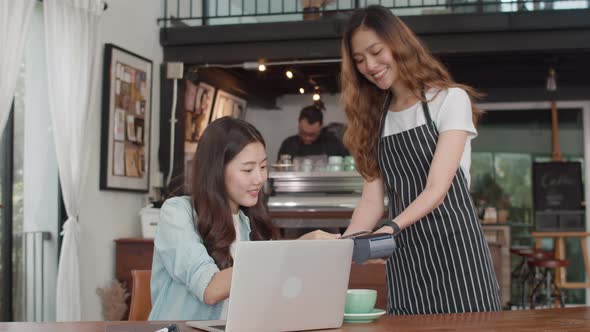 asian freelance women pay contactless credit card at coffee shop. Asian happy girl barista..