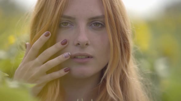 Close-up Portrait of Confident Sensual Woman with Red Hair and Green Eyes Standing on Sunflower