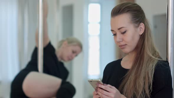 Cute Pole Dancer Taking a Break From Their Workout and Social Networking with a Cell Phone, While