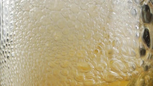 Close up of air bubbles created by someone blowing with straw into full glass of beer or soda