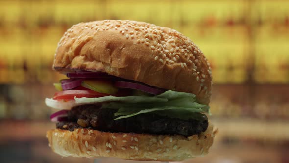 Burger with Beef Cutlet and Fresh Onions Appearing From the Dark Rotating in Slow Motion